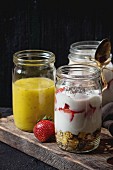 Healthy breakfast muesli, strawberries and yogurt with mango smoothie in glass mason jars