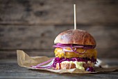 A hamburger with red cabbage, cheddar and red onions