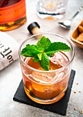 A bourbon cocktail on the rocks with mint