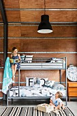 Bunk bed with metal frame and siblings in the children's room with wooden paneling