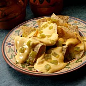 White corn tortilla chips with cheese sauce and chopped green peppers
