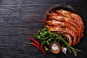 Raw fresh Prawns on metal plate on black burned wooden background copy space