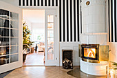Fire lit in round tiled stove against striped wall
