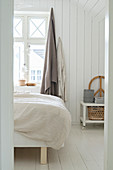 View into bedroom in pale natural shades with white board wall