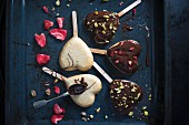Heart shaped vegan cakes on sticks, decorated with a dark beer glaze, freeze-dried strawberries and pistachios