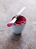 Beetroot spread in a small bowl with a knife