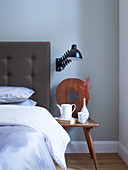 Old wooden chair used as bedside table next to bed with button-tufted headboard