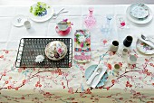 Rococo soup crockery, bowl and glass carafes on embroidered tablecloth on summery dining table