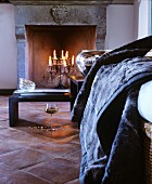 Romantic atmosphere with candelabra in open fireplace, glass of wine and fur blanket in front of black coffee tables