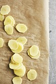 Raw potato slices for potato gratin on baking paper (seen from above)