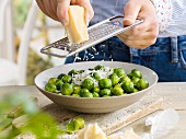A man grating cheese over brussel's sprouts