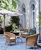 Wicker furniture and parasol on courtyard terrace of town villa