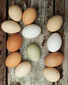 Verschiedenfarbige frische Eier auf Holzuntergrund