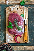 Raw pork with herbs, garlic, pepper and chilli on a chopping board
