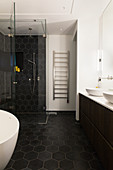 Black honeycomb tiles in bathroom with glass shower cabinet and heated towel rail
