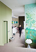 Woman walking through open-plan interior with green walls