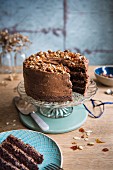Chocolate almond cake with brittle topping on a cake stand with a slice removed