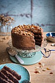 Schoko-Mandel-Torte mit Krokant auf Tortenständer, angeschnitten