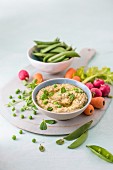 Houmous made of chickpeas, peas with mint and tahini, fresh vrgetables foe dipping on a side