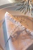 White linen napkin with drawn thread work and cow parsley seed head on plate