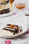 Salted caramel sauce being poured on a slice of buttercream layered wedding cake