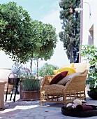 Wicker armchair with various cushions on traditional Mediterranean stone terrace