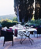 Gedeckter Tisch und Rattansessel auf mediterraner Terrasse