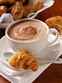 A cup of cappucino coffee and croissants
