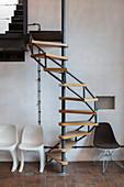 Designer chair next to spiral staircase against white wall