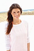 A brunette woman wearing a white jumper with an orange vest underneath