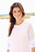 A brunette woman wearing a white jumper with an orange vest underneath