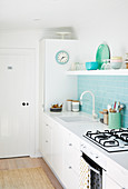 Pale blue tiled splashback and open shelf in bright kitchen