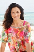 A brunette woman wearing a colourful T-shirt on the beach