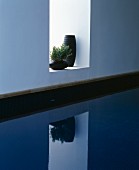Two black vases in niche above swimming pool