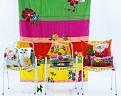 Colourful cushions on three chairs in front of striped cloth