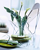 Table centrepiece in shades of green with calla lilies wrapped in napkins