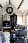 Grey sofa and zebra-skin rug in living room with display cabinet under wall-mounted clock