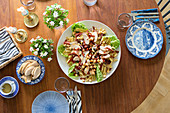 Gedeckter Tisch mit blauem Geschirr und Salat von oben