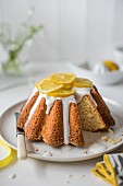 Lemon sponge cake with lemon icing and fresh lemon slices, slice removed