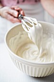 Whipping cream in a mixing bowl with a whisk