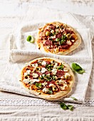 Two rustic pizzas with chorizo, green olives and basil leaves