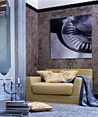 Senfgelbes Sofa unter moderner Fotografie vor einer Marmorwand