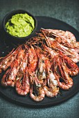 Roasted red shrimps with guacamole avocado sauce in slate stone black plate