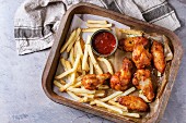Fast food fried spicy chicken legs, wings and french fries potatoes with salt and ketchup