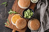 Ingredients for vegan burger. Veggie cheese and onion cutlets, yogurt sauce, hamburger buns, herbs and avocado salad