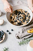 A woman's hand mixing blueberry muffin batter