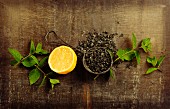 Dry tea with mint and lemon on wooden table, top view