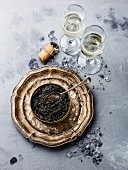 Schwarzer Störkaviar in Metalldose auf Silbertablett daneben Champagnergläser
