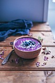 Blueberry acai smoothie bowl topped with blueberries, shredded coconut and cacao nibs on rustic wooden table