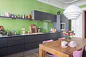 Dining table in kitchen with grey cabinets, green wall and stucco ceiling